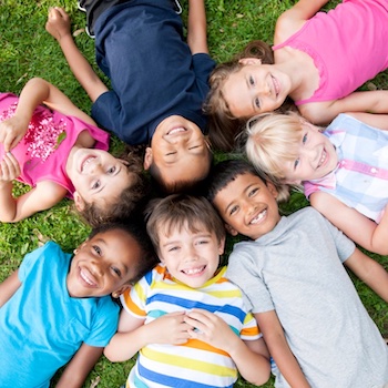 group of children laying on the grass in a circle